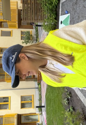 Glad medarbetare på ett event på en innergård i Vega med en keps med Stena Fastigheters logga