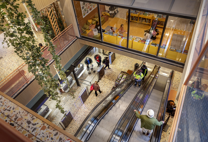 Bild på personer som åker i en rulltrappa i Fisksätra Centrum, bilden är tagen ovanifrån.