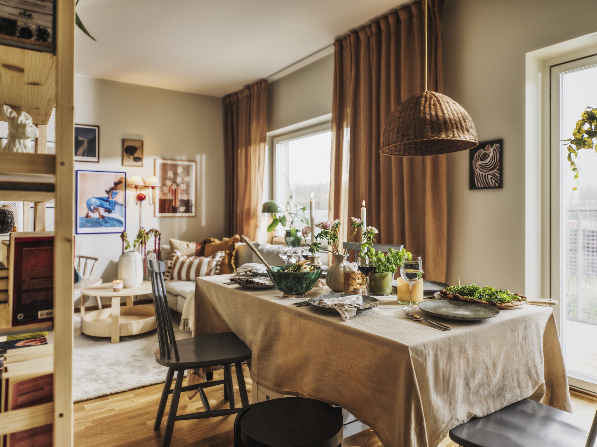 Vardagsrum med soffa och bokhylla samt uppdukat matbord