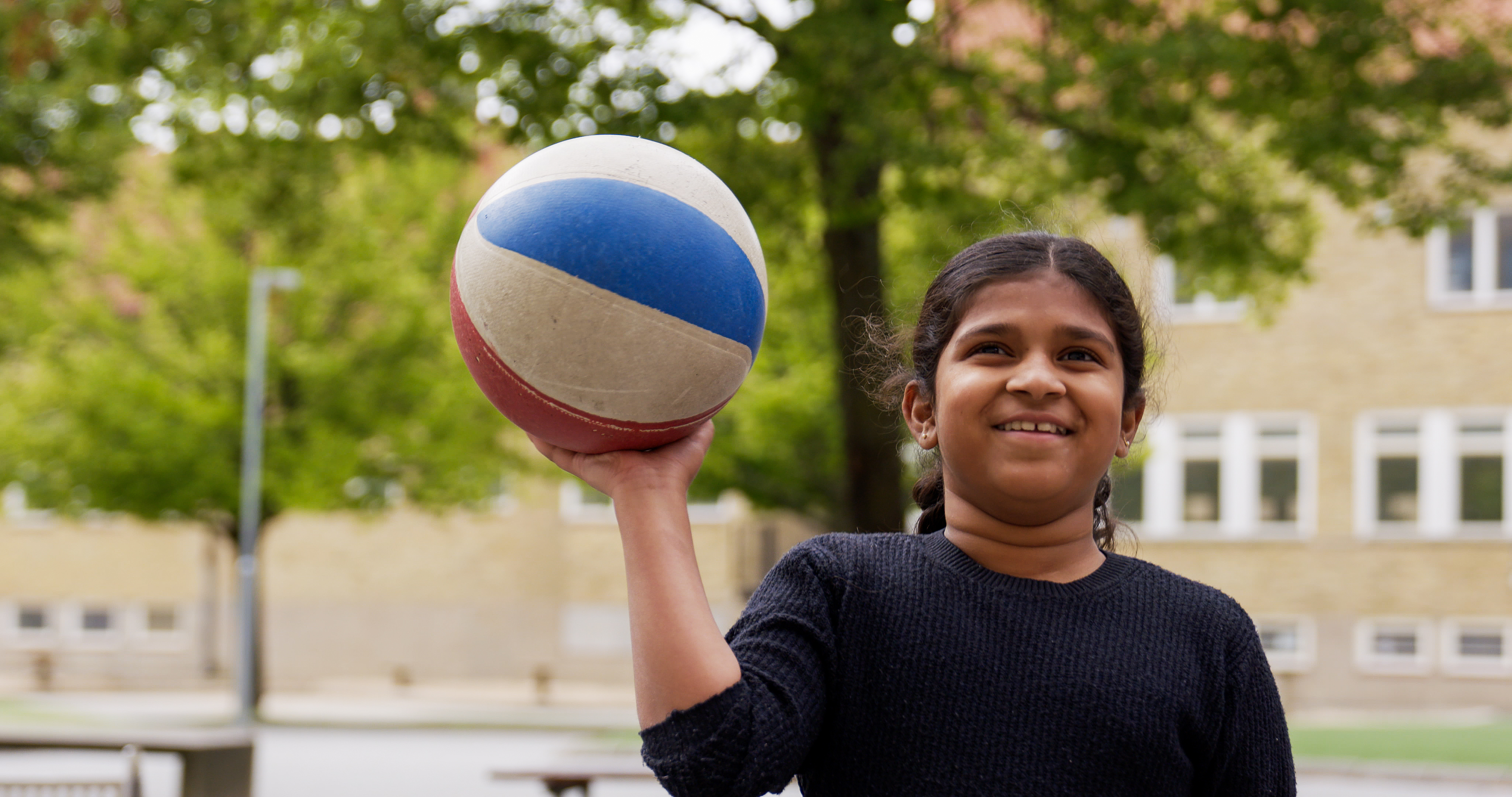 Tjej på sommarskolan som håller en basketboll. 