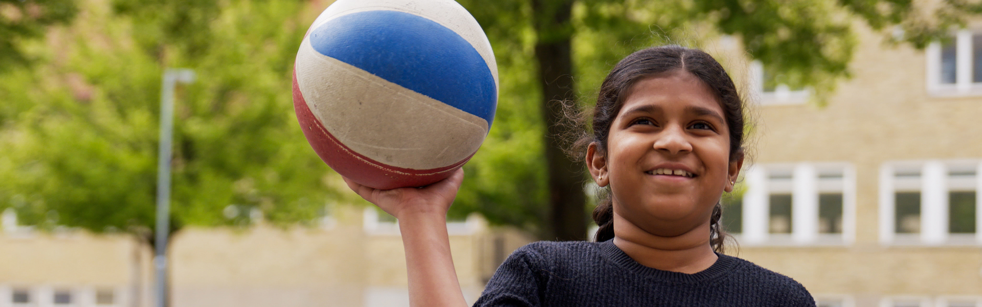 Tjej på sommarskolan som håller en basketboll. 