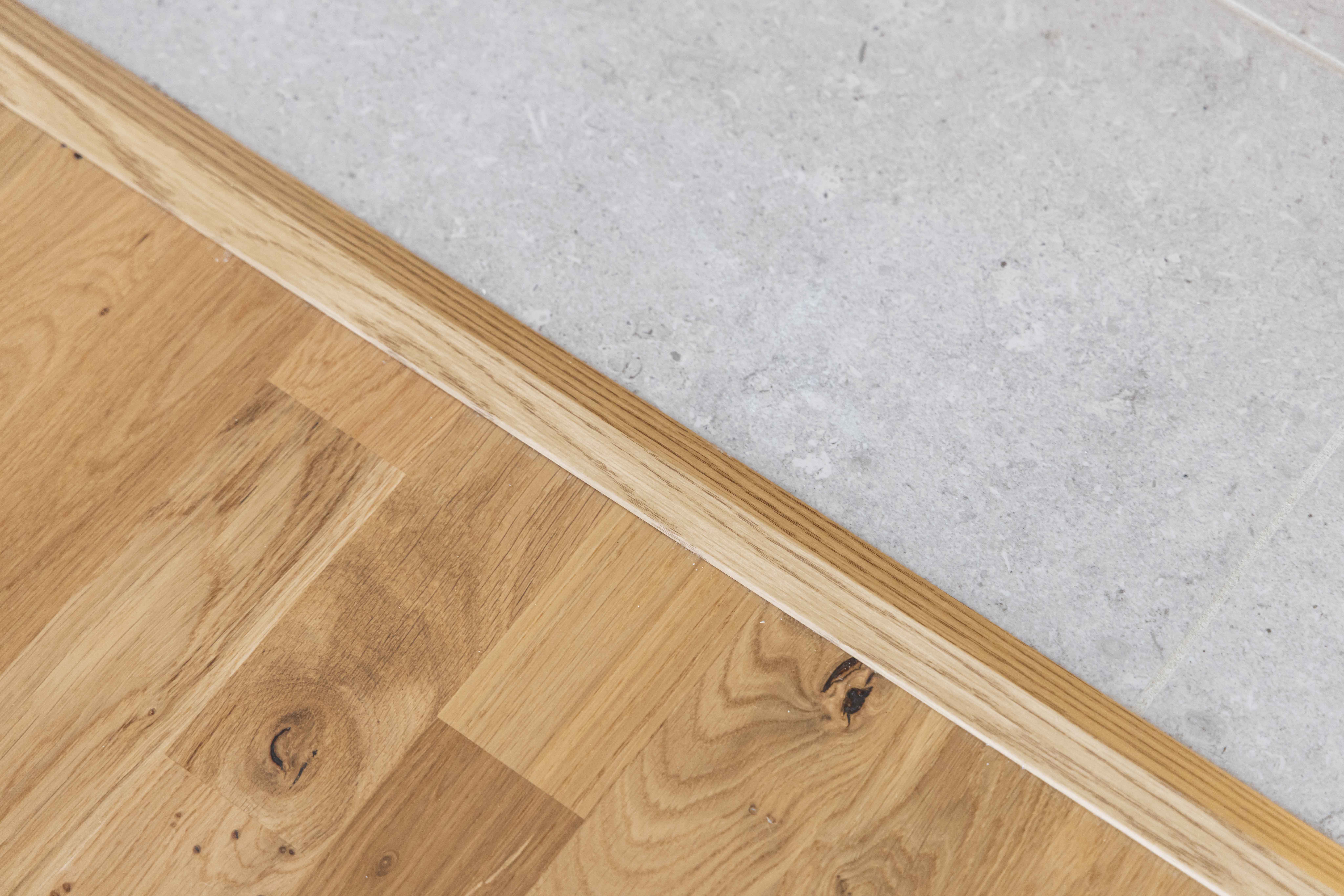 Detaljbild från en plusrenoverad lägenhet med fokus på parkettgolv och klinker i hall