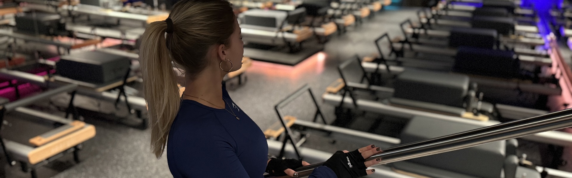 Person med träningskläder som tittar ut mot pilatesmaskinerna.
