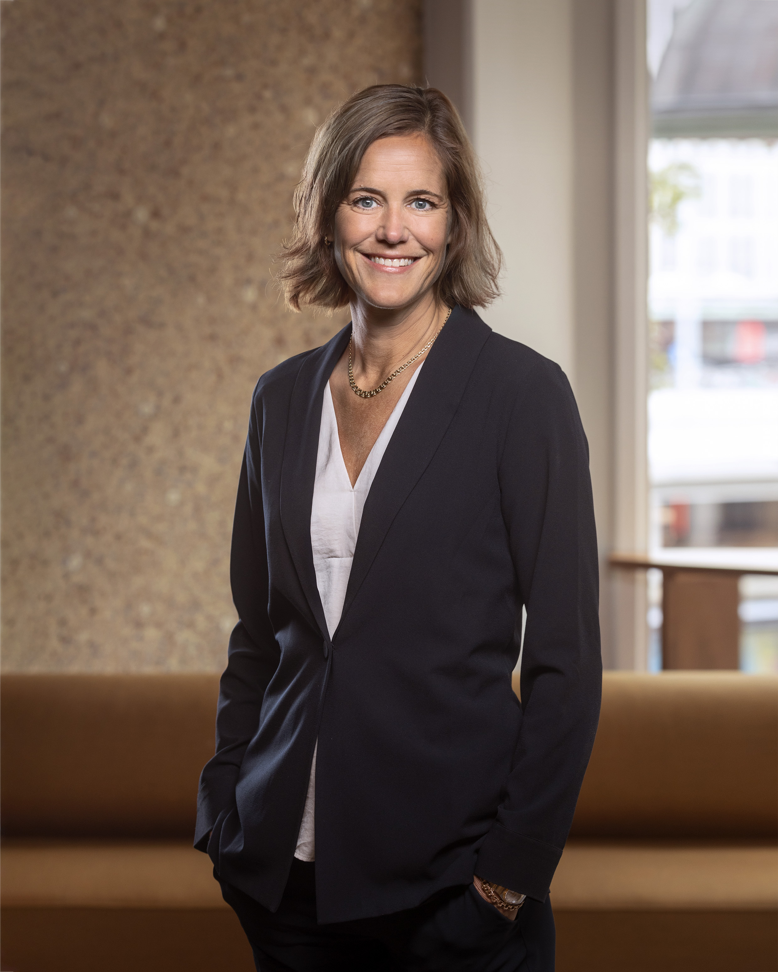 Fotot visar en kvinna, Cecilia Fasth koncern VD för Stena Fastigheter,  i mörk kavaj och ljus topp som står inomhus framför en brun soffa. Bakgrunden består av en ljus vägg till vänster och ett stort fönster till höger. Hon tittar in i kameran och ler.
