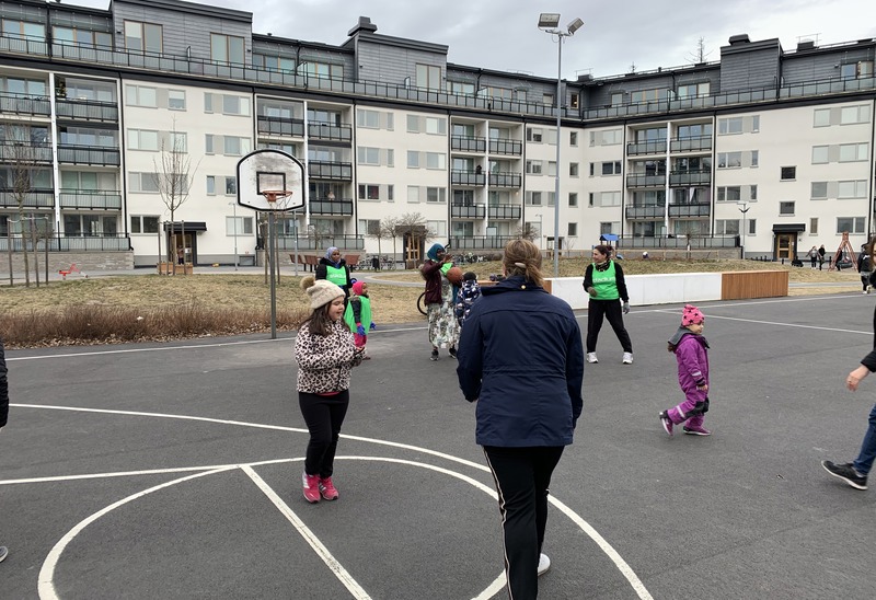 Barn i olika åldrar leker på en basketplan utomhus.