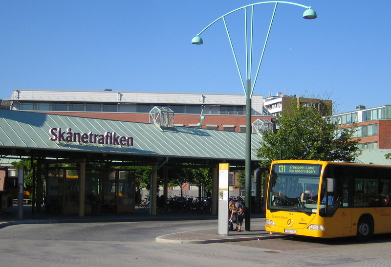 Bussterminalen vid Skånetrafiken, med en gul stadsbuss redo för avgång. Den gröna byggnaden i bakgrunden fungerar som vänthall, tydligt märkt med Skånetrafikens logga.