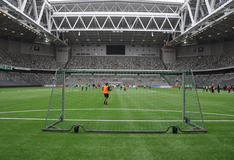 En fotbollsarena fotad från kortsidan med barn som spelar fotboll.