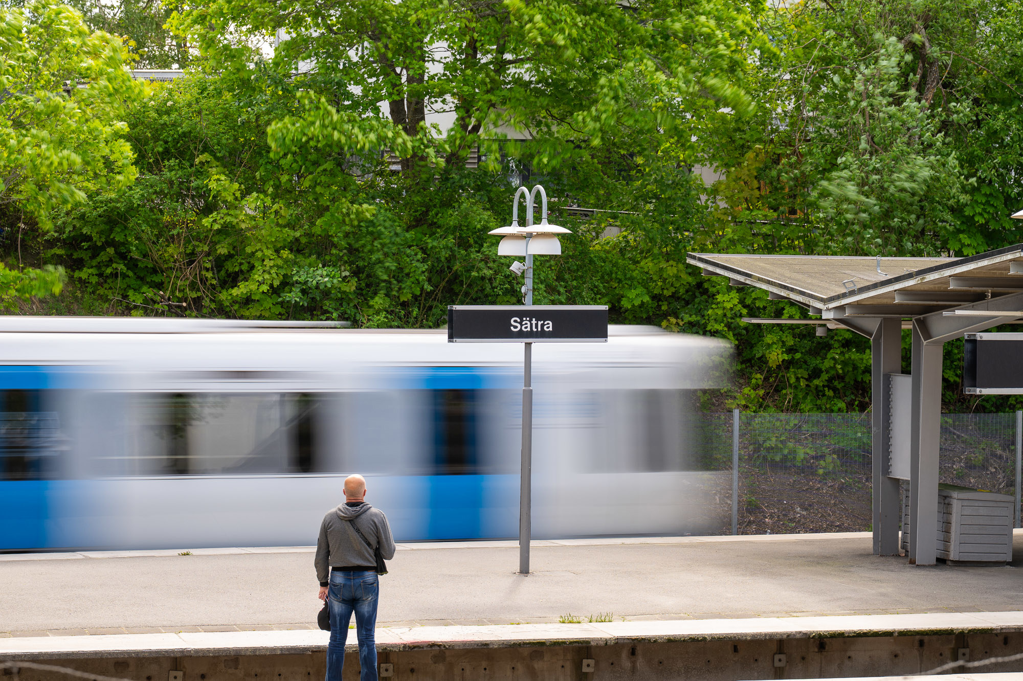 man på Sätras tunnelbaneperrong där tunnelbanan swischar i bakgrunden