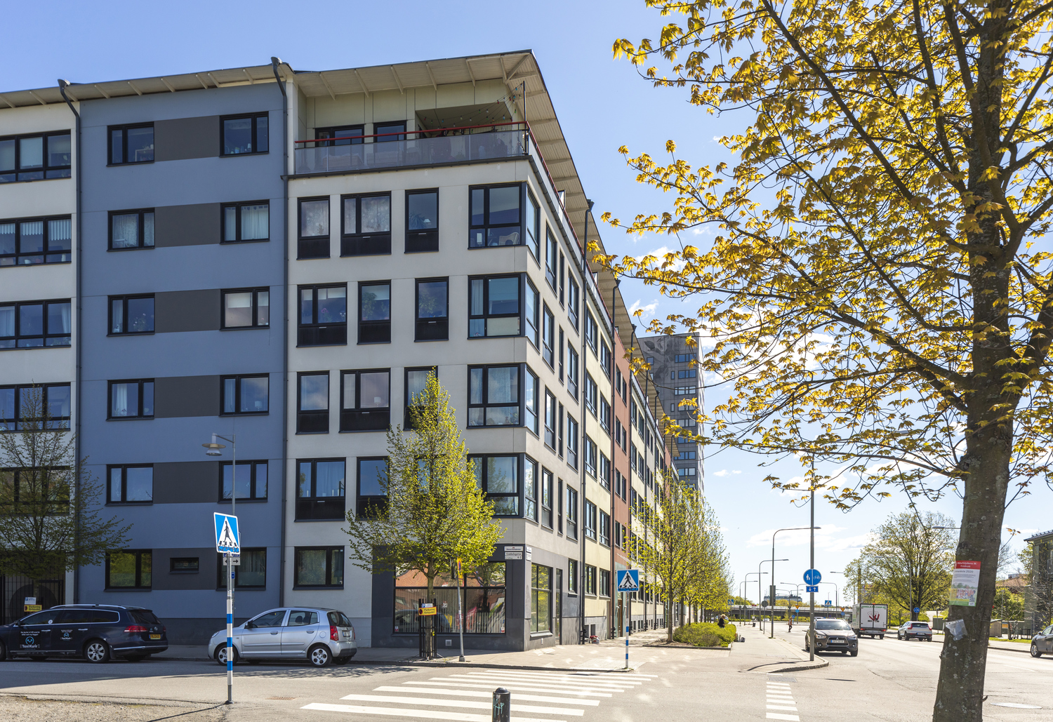 Flerfamiljshus i vitt med ett blått parti och svarta ramar runt fönstren.