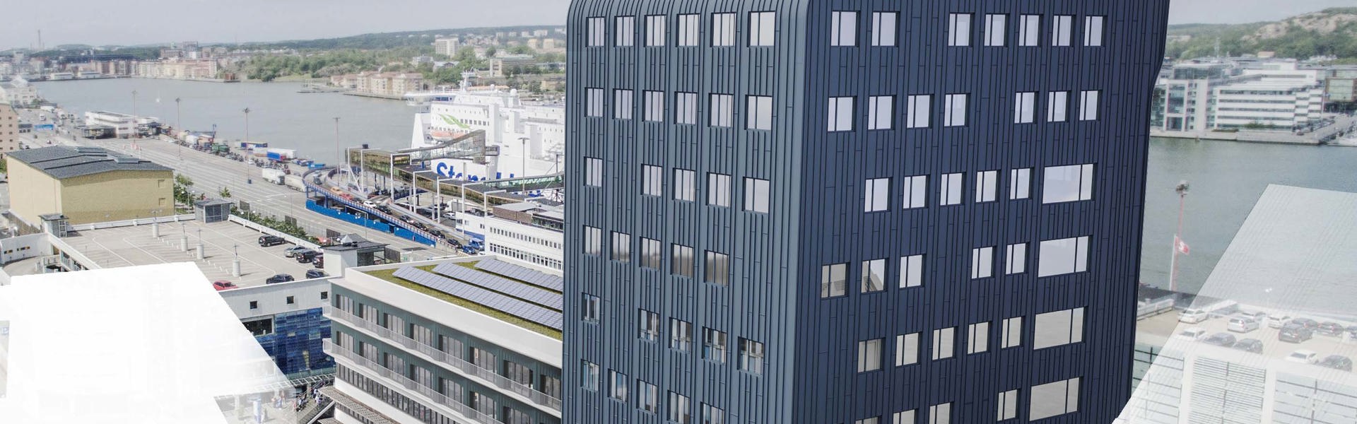 En modern hög byggnad med mörkblå fasad och stora fönster. Bilden är i fågelperspektiv